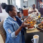 Family members pass around food at family dining table