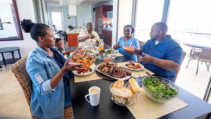 Family members pass around food at family dining table