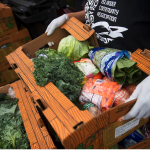 Food bank employee carries box of vegetables